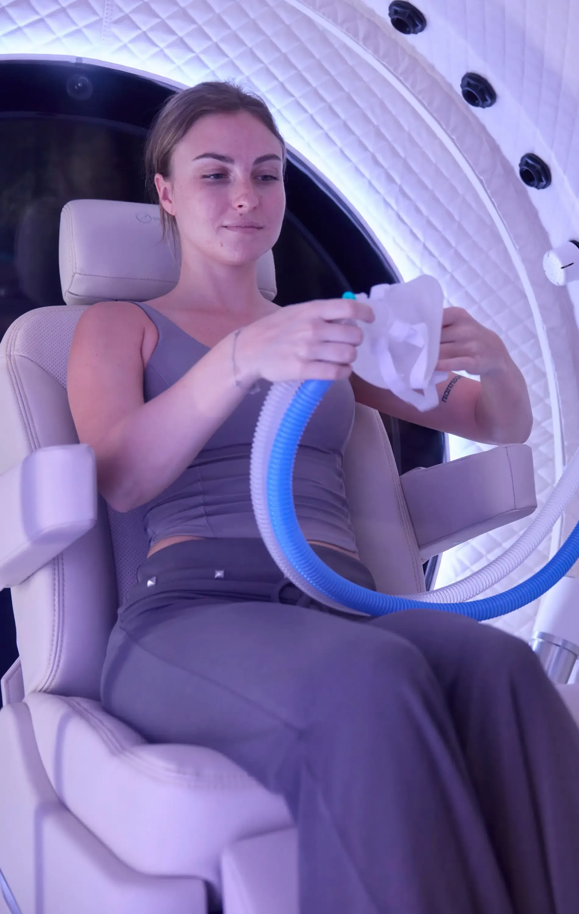 Seated in the chamber, holding the oxygen mask and its hose before putting it on
