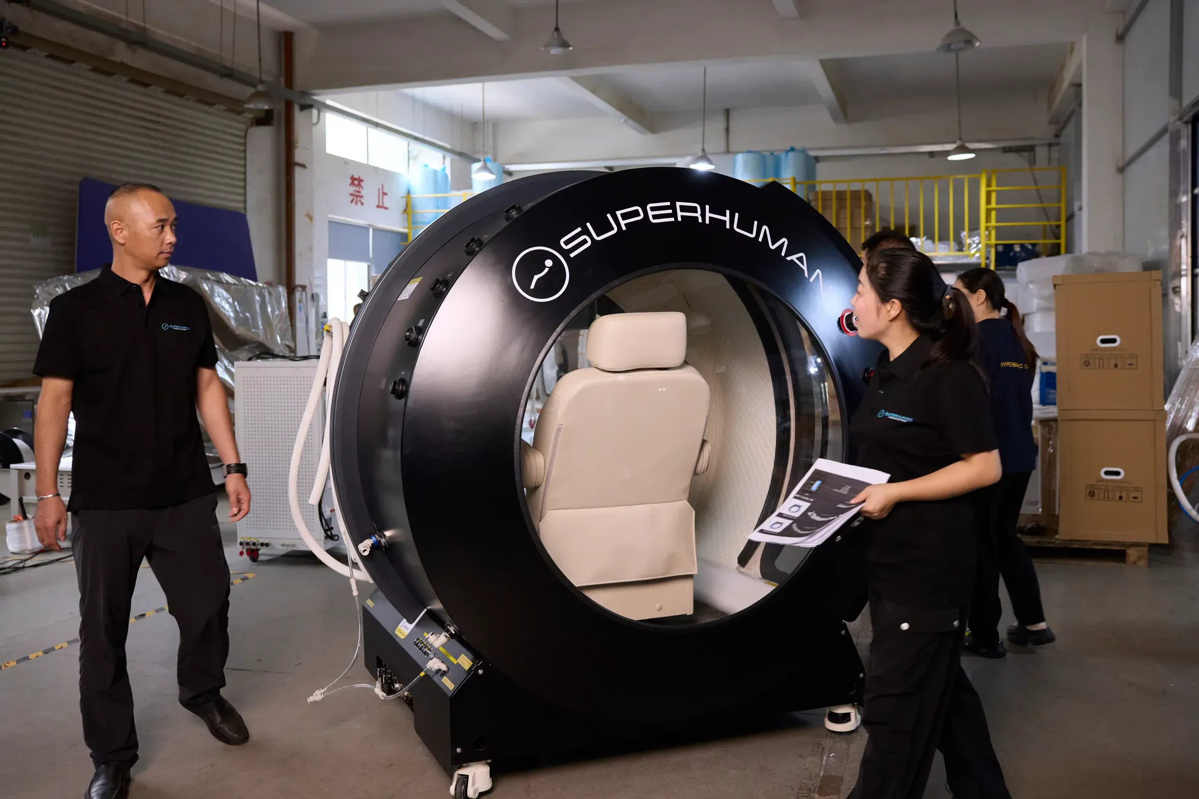 Superhuman team walking a Model X hyperbaric chamber through final assembly on the factory floor