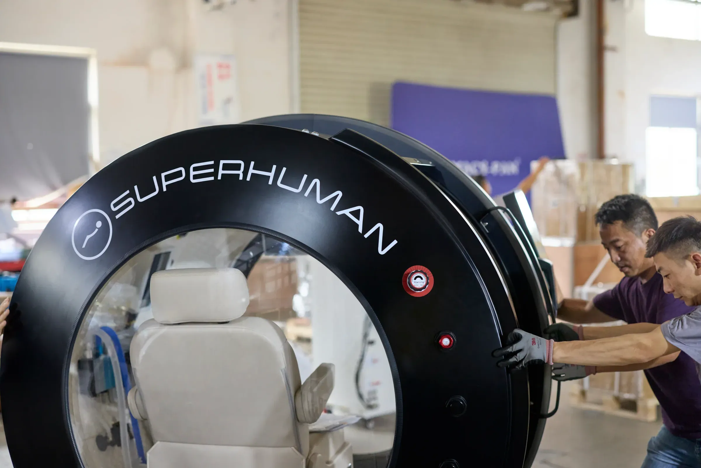 Technicians positioning a Superhuman X hyperbaric chamber on the ASME-certified production line