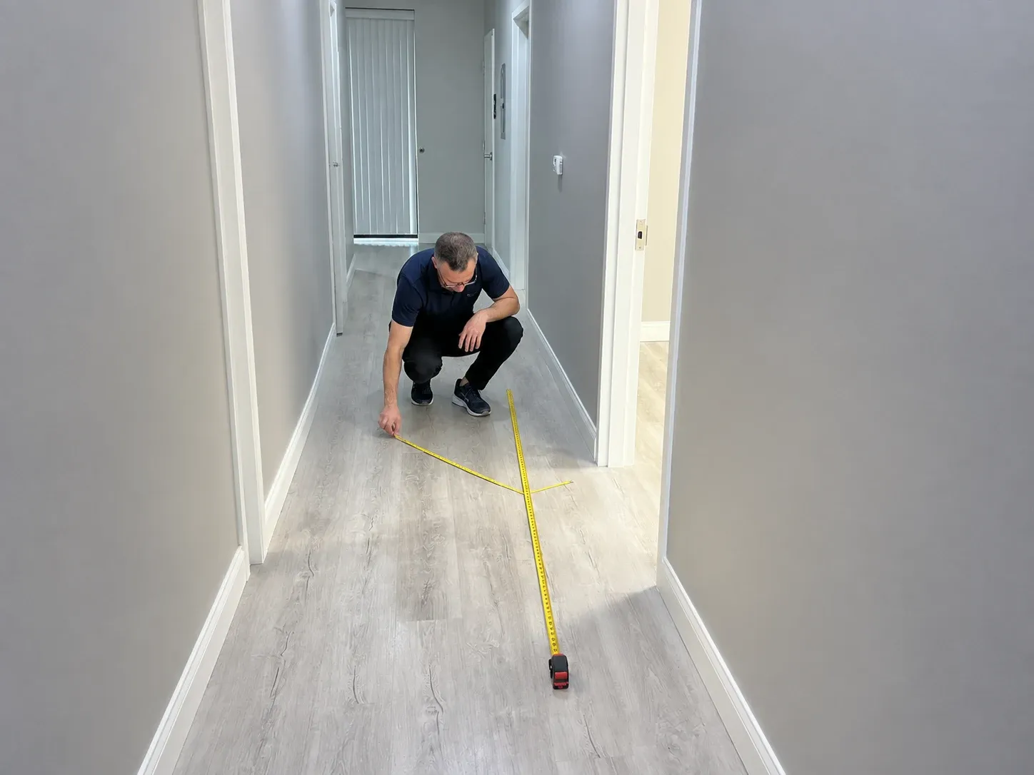 A Superhuman specialist measuring a client’s hallway with a tape measure during a site survey