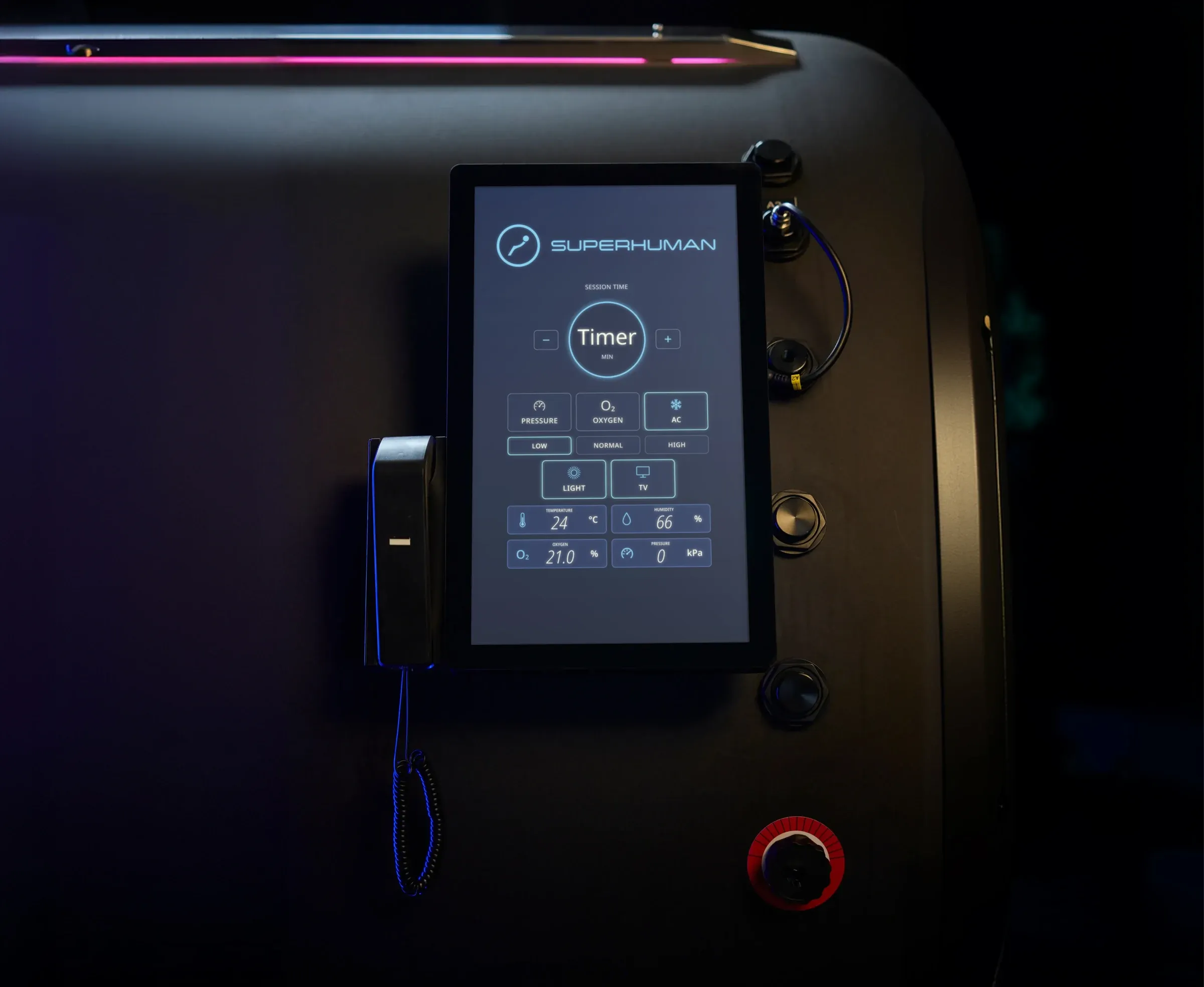 The control panel on the outside of a Superhuman hard-shell chamber, with the oxygen and pressure readouts on screen and the intercom handset beside it