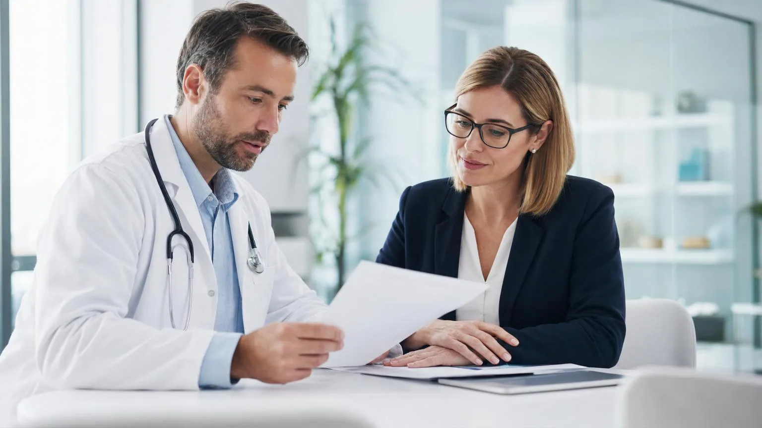 Physician in a white coat and a clinic administrator reviewing treatment documentation together