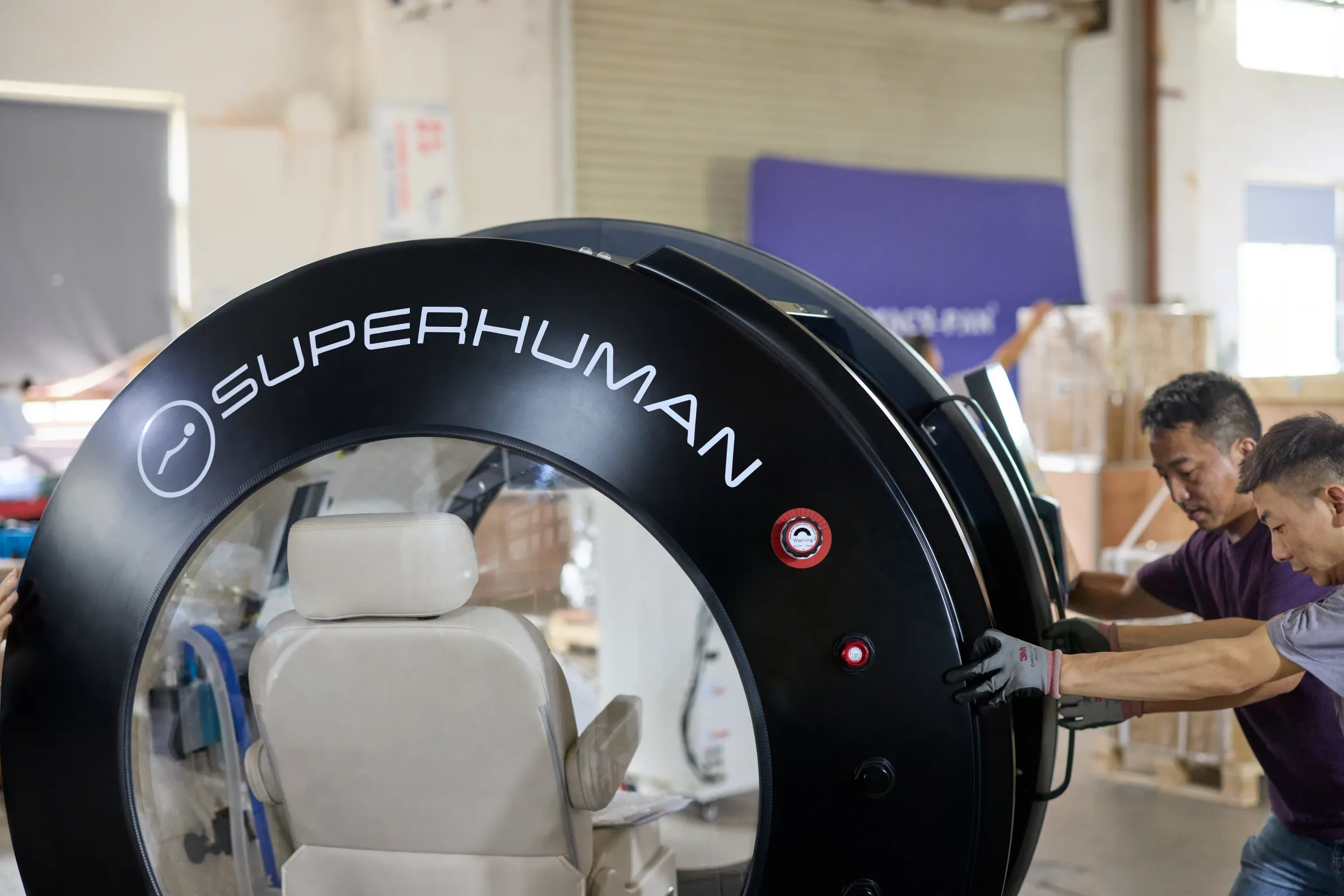 Installation team positioning a Superhuman X seated hyperbaric chamber inside a facility